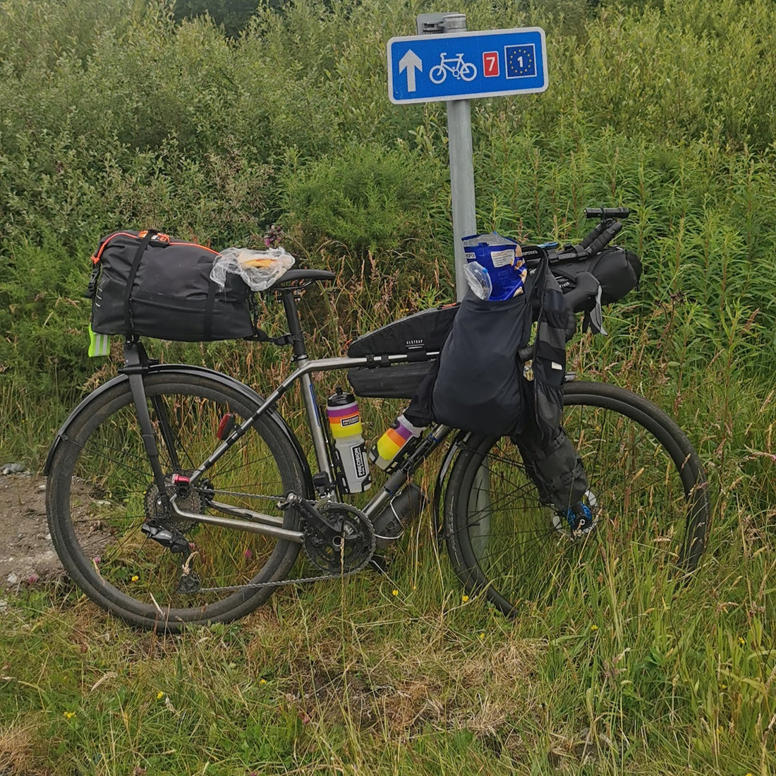 A well packed bike leans against a post. 