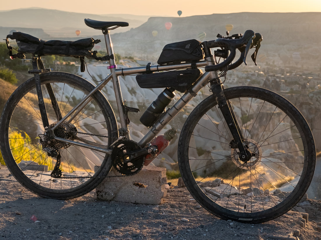 Dirty adventure bike with bags strapped to frame in front of a canyon. 