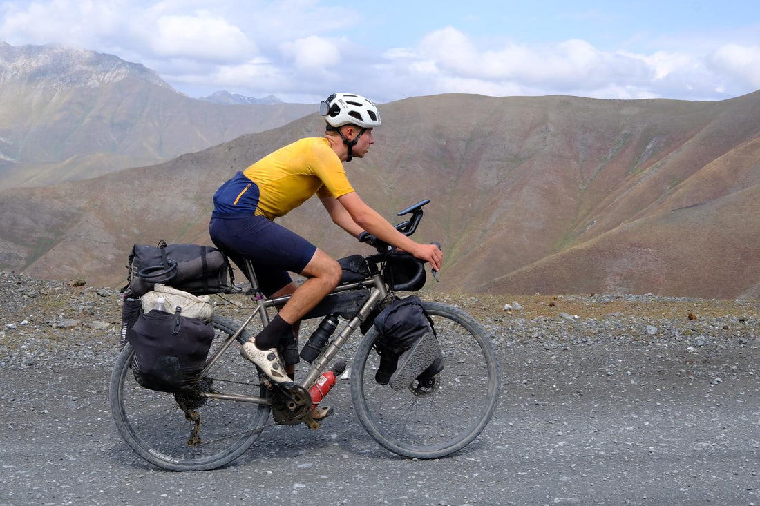 Man with a well packed bike cycles on a rocky surface.